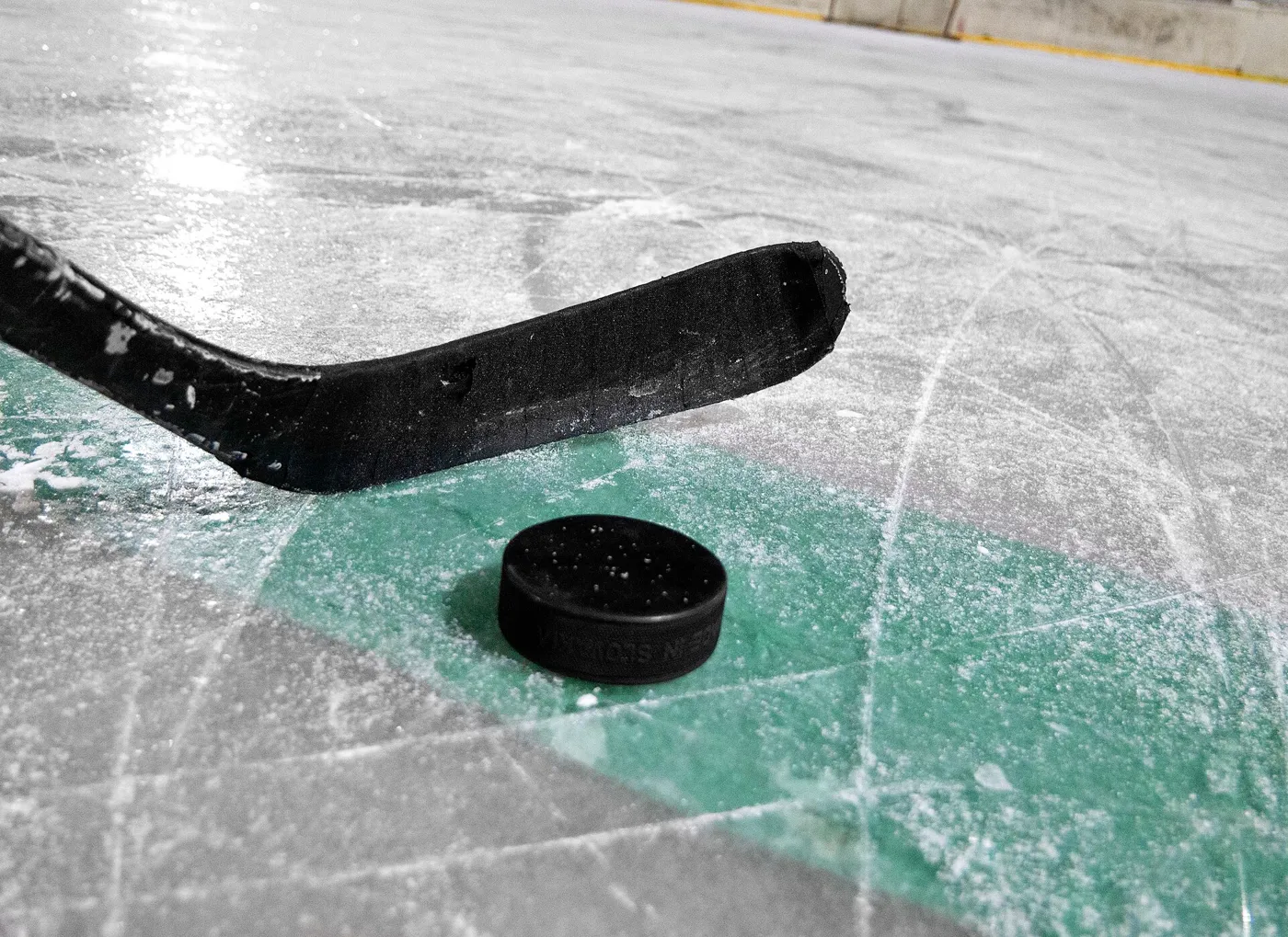 bastón y disco de hockey en una pista